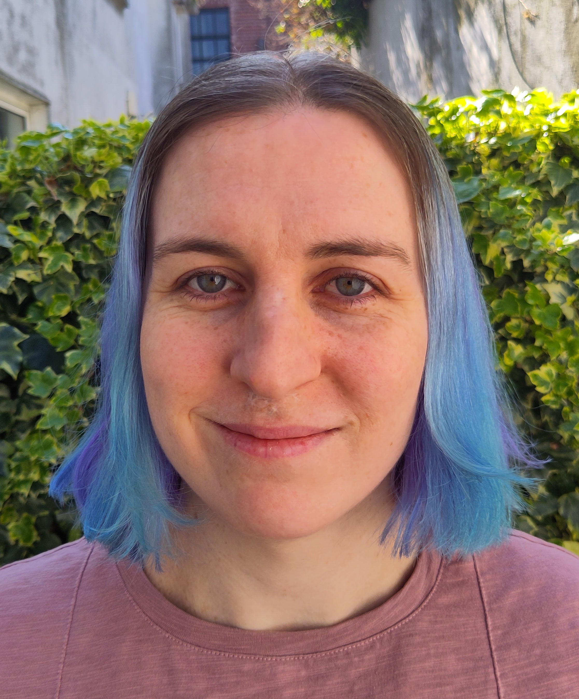 A woman with blue hair smiling